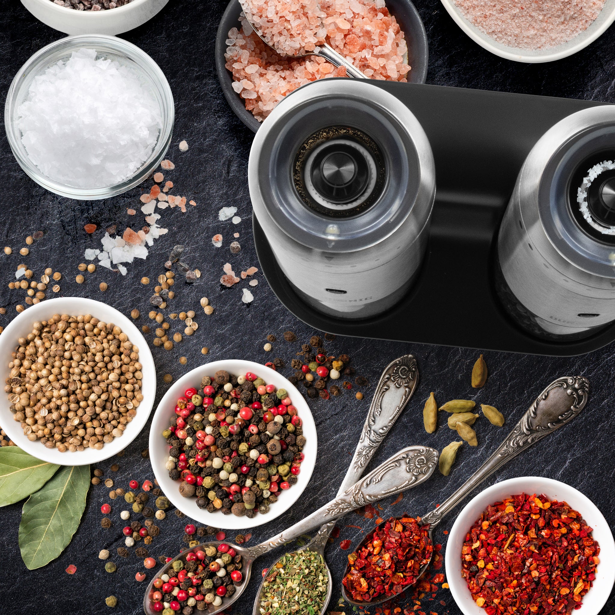 Duronic Electric Salt and Pepper Grinder Set on a black tray surrounded by colorful gourmet spices.