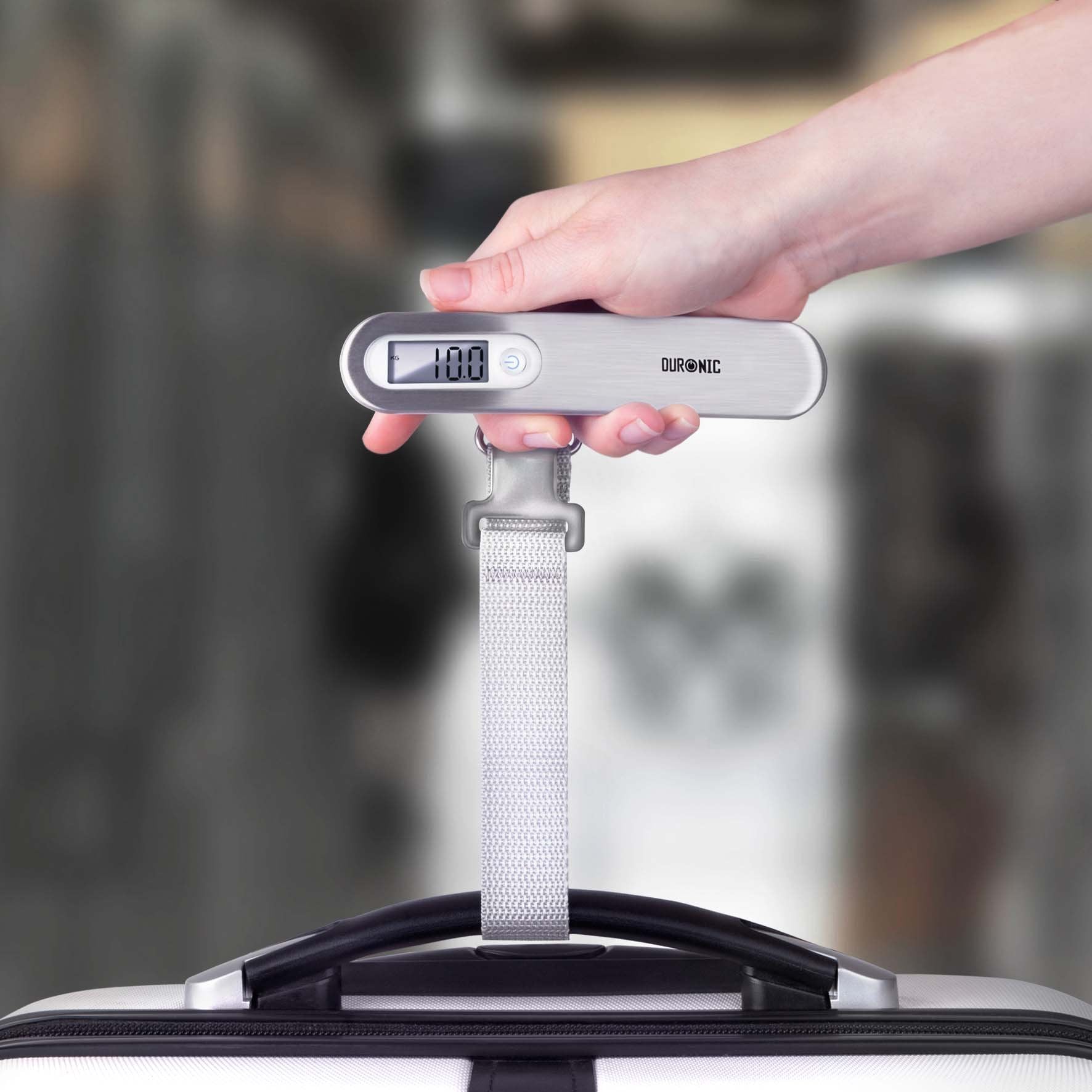 Duronic Luggage Scale Travel Bag Weigh weighing a silver suitcase, displaying 10.0 kilograms.