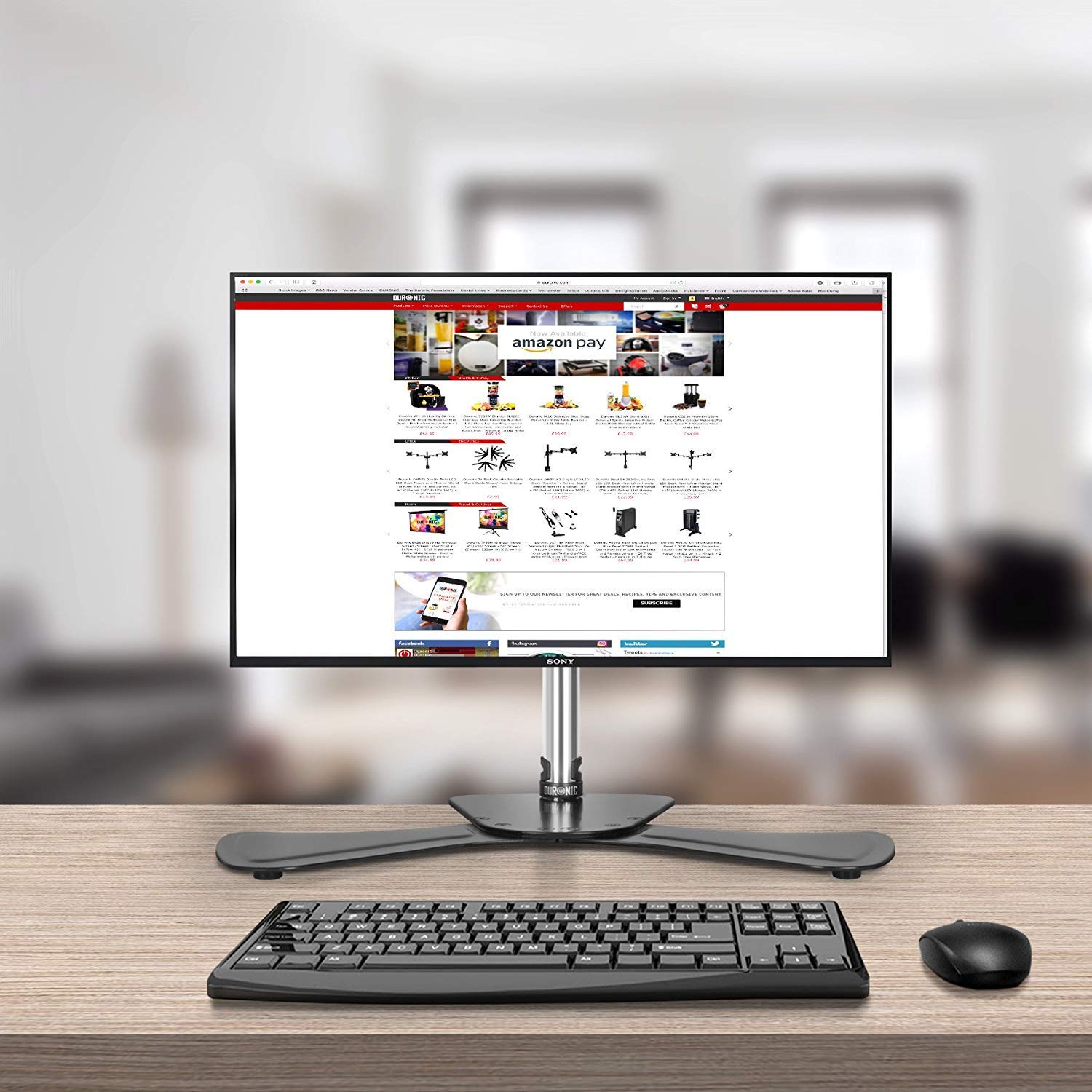 Duronic Computer Monitor Arms Stand with a keyboard and mouse on a wooden desk.