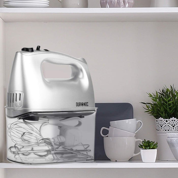 Duronic HM4 SR silver hand mixer with attachments in storage case placed on aesthetic shelf alongside other kitchen items
