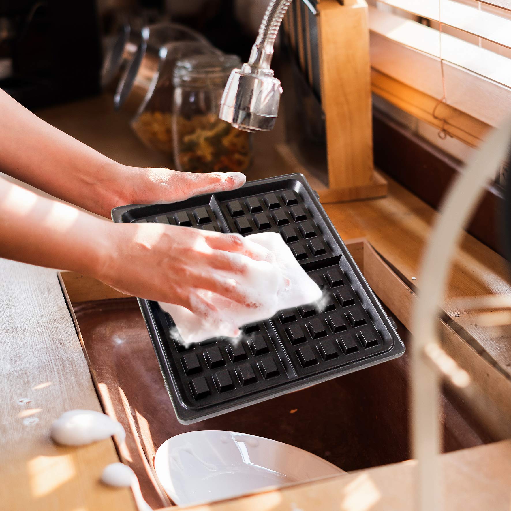 Duronic WM60 electric waffle maker irons being cleaned under kitchen tap with soap to show easy cleaning