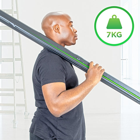 A man carries a lightweight 7kg black projection screen over his shoulder in a bright studio setting with a ladder in the background.