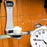 Duronic Digital Kitchen Scale weighing flour on a glass platform next to a white alarm clock.