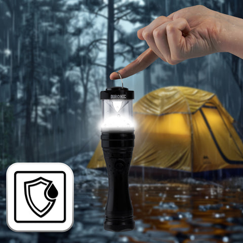 Duronic LED Torch hangs from a person's finger against a rainy forest backdrop with a glowing yellow tent.