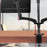 Duronic Quad Monitor Arm Stand clamped to a wooden desk holding a computer monitor.