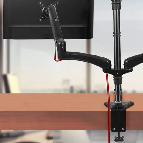 Duronic Quad Monitor Arm Stand clamped to a wooden desk holding a computer monitor.