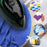 Duronic Travel Black Iron smoothing out blue fabric, surrounded by circular icons showcasing its versatility for quilting, melty bead crafts, iron-on transfers, and travel.