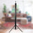 Duronic Tripod Projector Screen Portable projector screen rolled up vertically on a black tripod stand inside a living room.