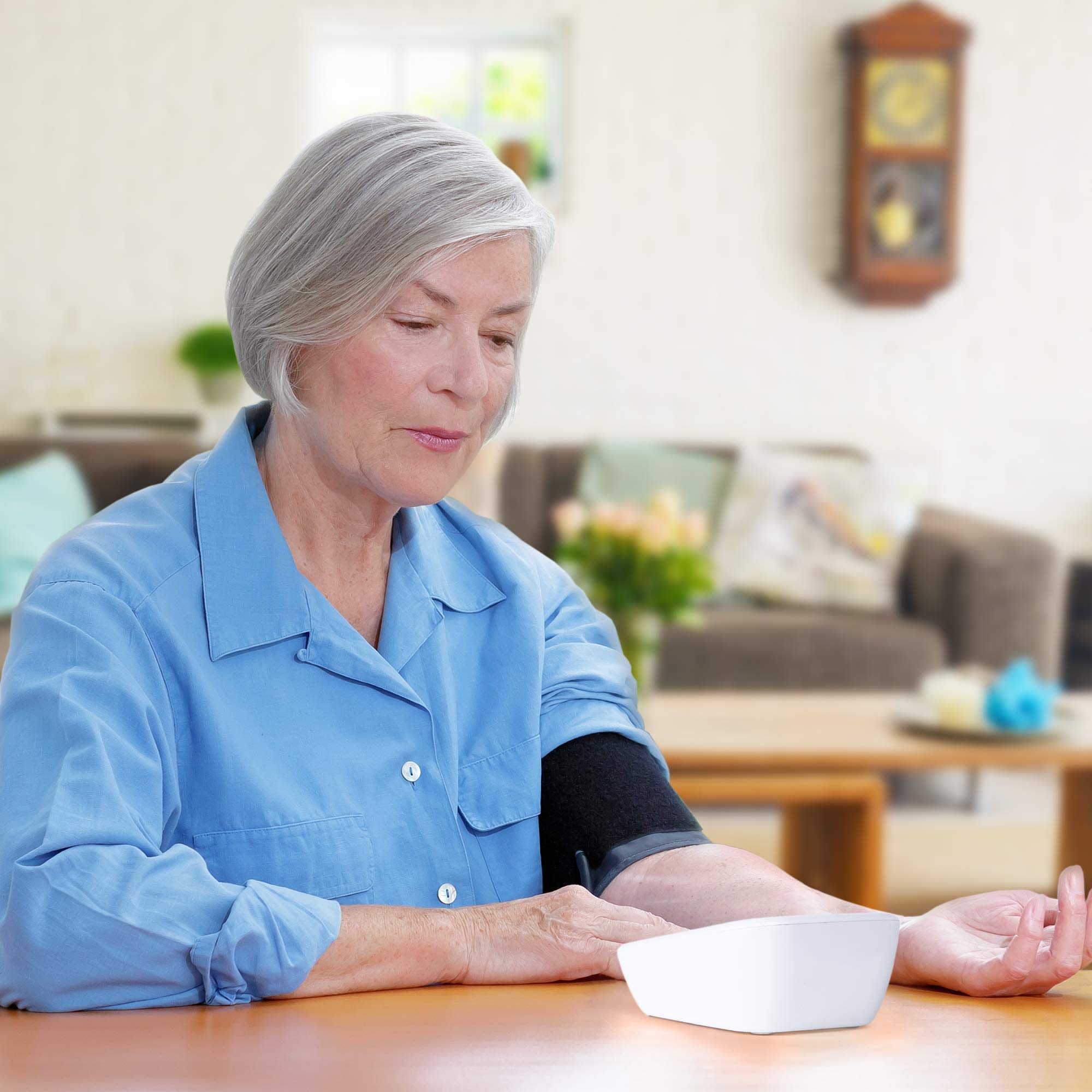 Duronic Blood Pressure Monitor with older woman in a blue shirt uses an automatic blood pressure monitor at home