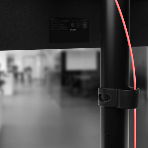 Duronic DM15D1 Monitor Stand with integrated cable management clip holding a red wire.