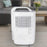 Duronic Dehumidifier featuring a built-in handle, air intake grille, and technical specification label in a living room setting.