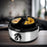 Duronic EB40 BK electric egg boiler cooking eggs in the omelette trays provided, placed aesthetically on a table