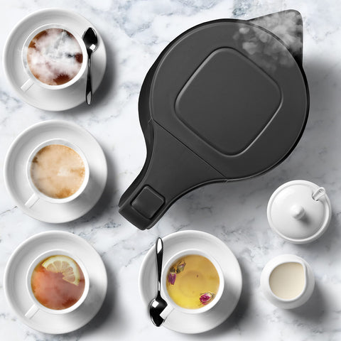 Duronic Electric Kettle surrounded by four assorted tea cups, cream, and sugar.