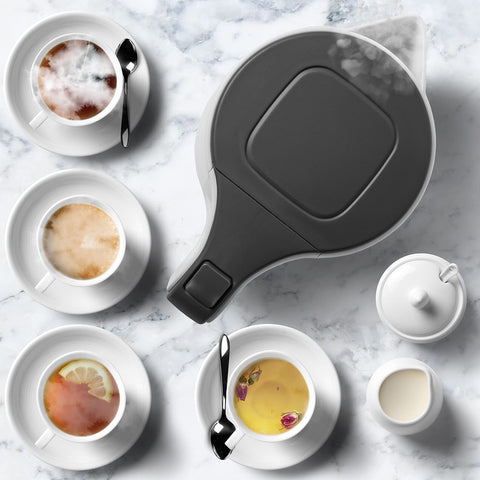 Duronic Electric Kettle surrounded by four assorted tea cups on marble.