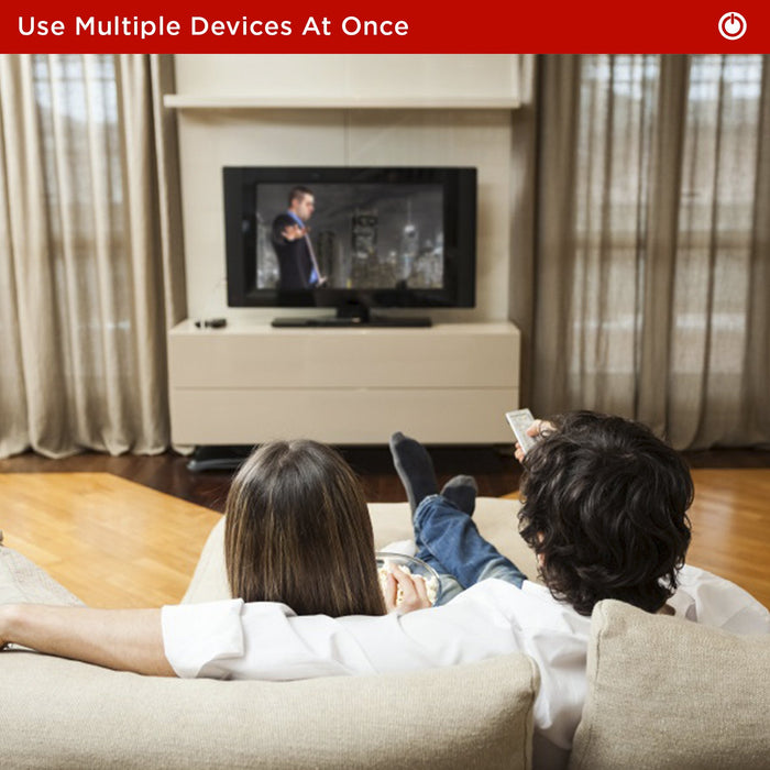 Duronic HDMI Splitter couple relaxes on a sofa watching television while using a remote control, illustrating a modern home entertainment experience.