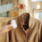 Duronic Lint Roller cleaning a tan wool coat hanging on a gold hanger.