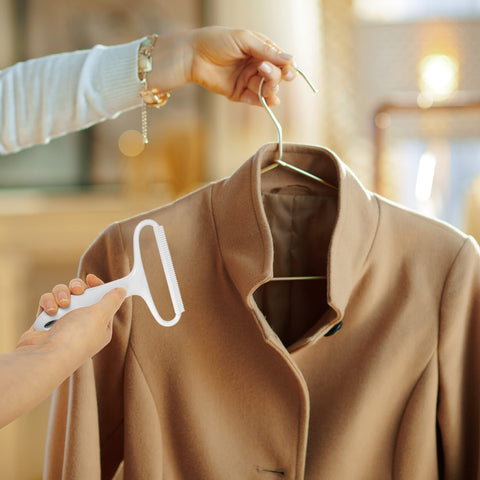 Duronic Lint Shaver being used to clean a tan wool coat on a hanger.