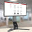 Duronic Monitor Arm Stand supporting a widescreen computer screen on a wooden table.