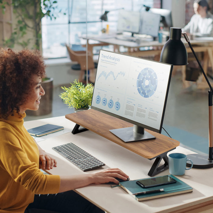 Duronic Monitor Stand Riser on a white desk with a woman working in an office.