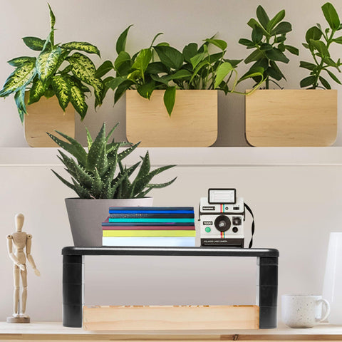 Duronic Monitor Stand Riser on shelf holding notebooks, vintage camera, and aloe vera potted plant.