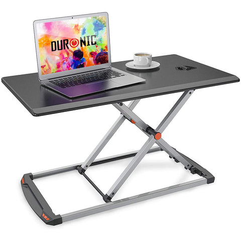 Duronic Sit-Stand Desk featuring a height-adjustable silver X-frame base, shown holding a laptop and a cup of coffee.