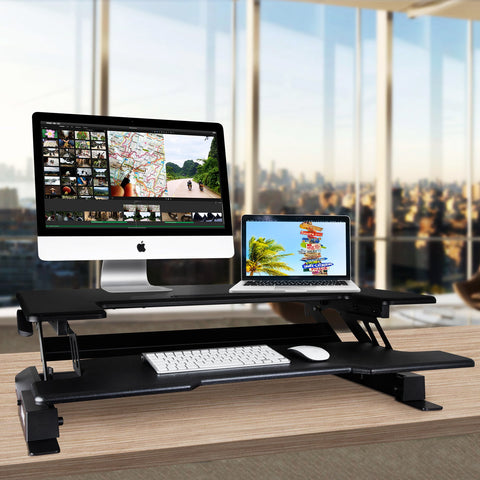 Duronic Sit-Stand Desk with dual monitors, keyboard, and mouse on a wooden table.