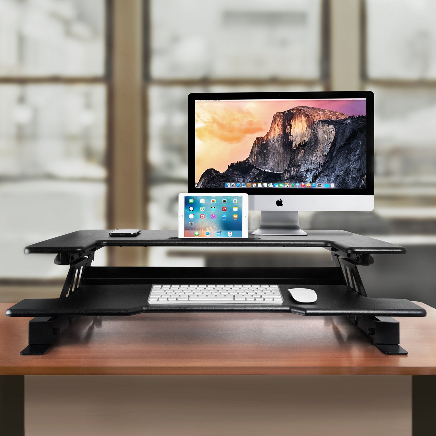 Duronic Sit-Stand Desk with iMac, iPad, keyboard, and mouse on wooden desk.