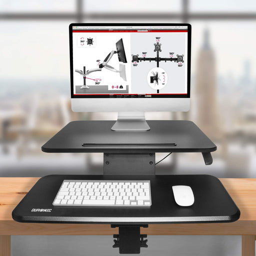 Duronic Sit-Stand Desk with keyboard tray clamped to wooden table holding a computer.