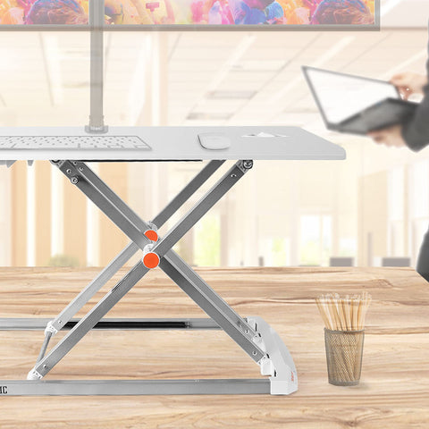 Duronic Sit-Stand Desk with x-shaped silver legs on a wooden office tabletop background.