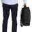 Duronic Travel Cabin Bags with Man holding a black commuter backpack by its top handle next to his leg.