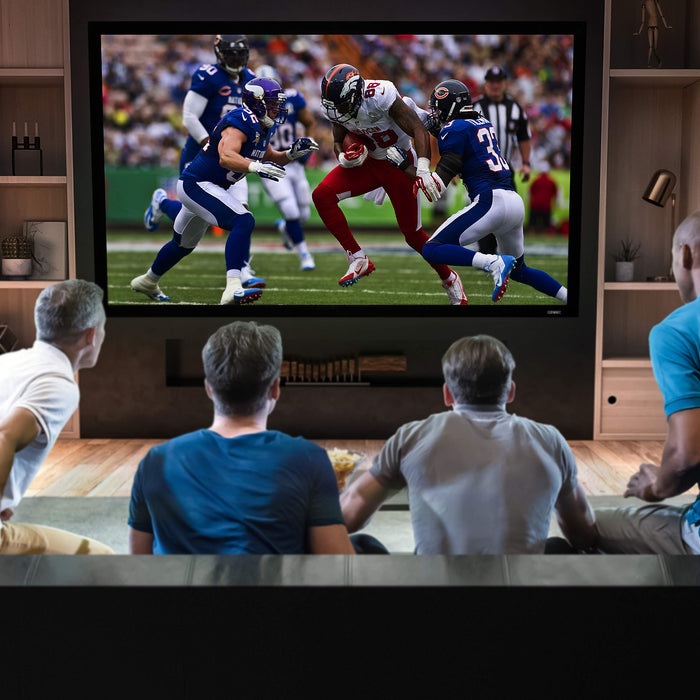 Four men watching an American football game on a large home theater projector screen.
